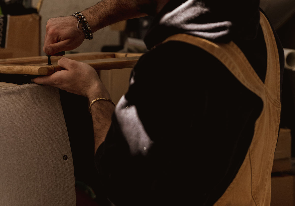 Person wearing a brown apron working on a wooden surface with a blurred background