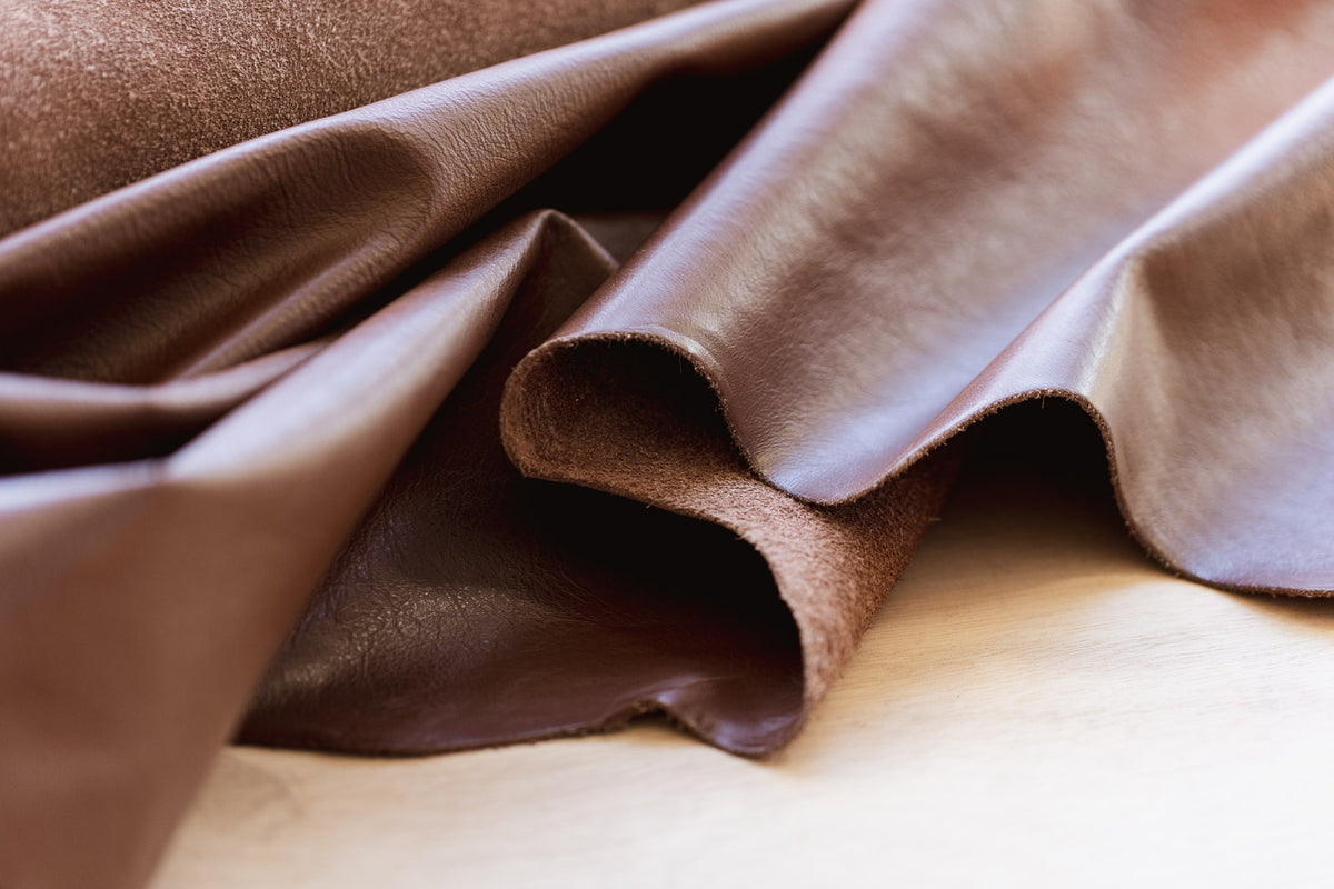 Close-up of brown leather fabric with folds on a light background