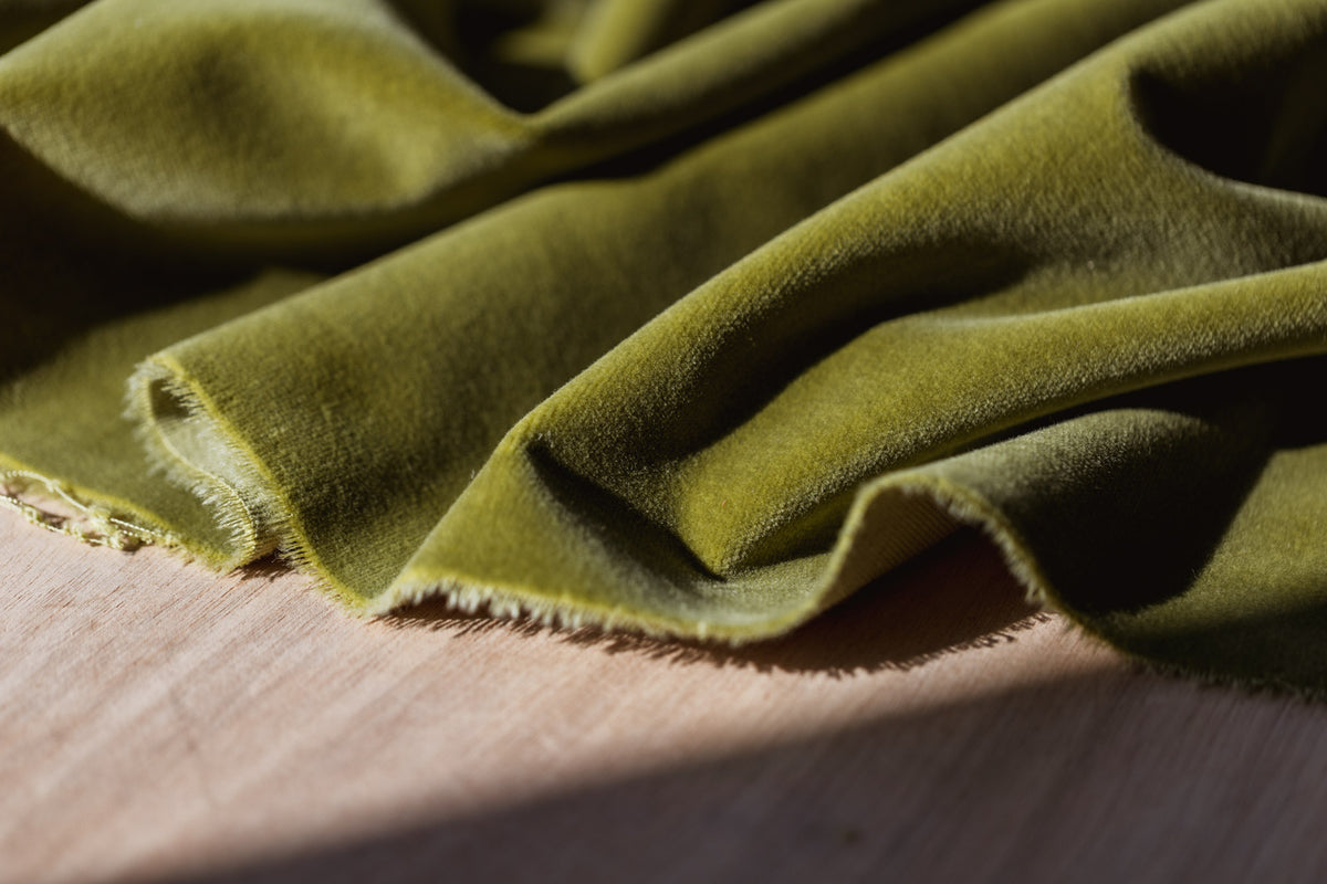 Close-up of green velvet fabric on a wooden surface