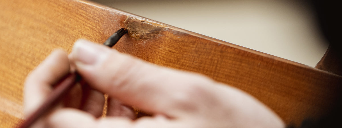 Hand using a small tool on a wooden surface