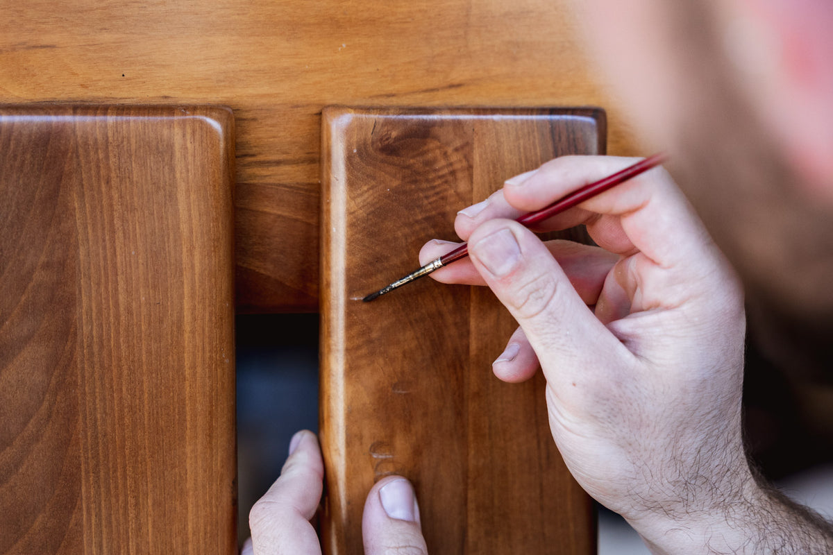 Person applying a wood finish to a wooden surface using a brush