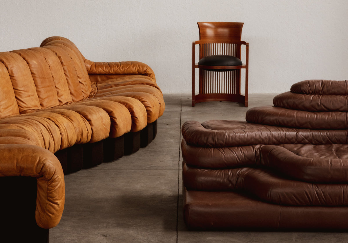 Two brown leather sofas and a chair in a minimalistic room.